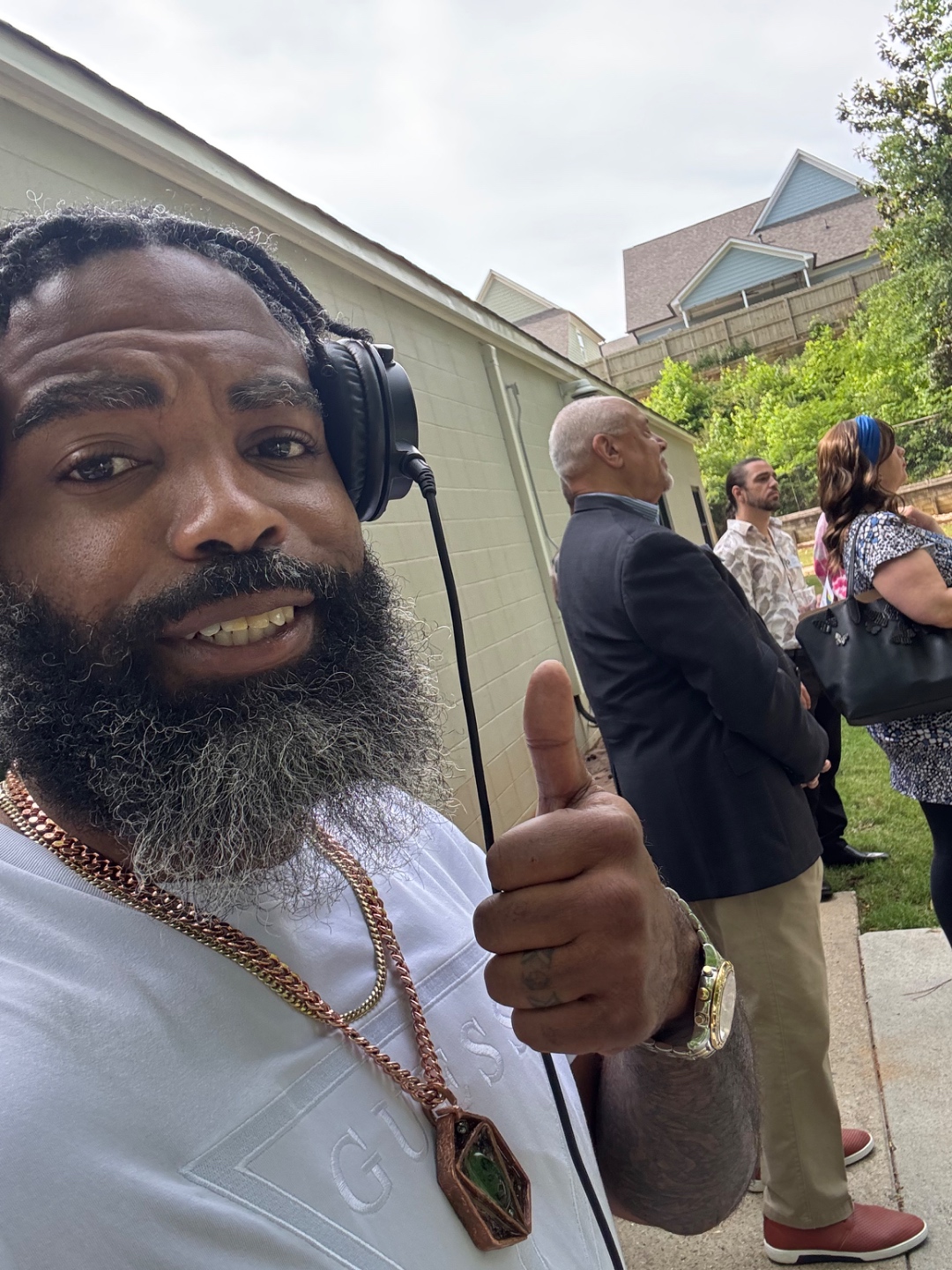 DJ Capo The Don with headphones and gold chain giving a thumbs up at a live outdoor event